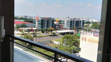 A balcony with a table and chairs, overlooking a cityscape with modern buildings and a McDonald's.
