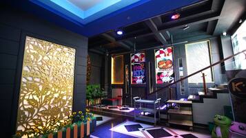 A modern interior with a reception desk, a staircase, and a neon sign advertising a grill.