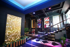 A modern interior with a reception desk, a staircase, and a neon sign advertising a grill.