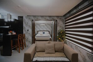 Un ambiente compatto con angolo cottura, un letto e una zona relax.