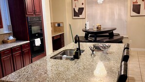 A kitchen with granite countertops, a built-in oven, and a dining area with a round table and chairs. - Luxury Retreat Hot Tub, Office & Gym (Arlington)