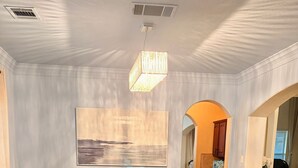 A dining room with a wooden table, white chairs, a vase with flowers, and a painting on the wall. - Luxury Retreat Hot Tub, Office & Gym (Arlington)