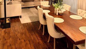 A modern living room with a wooden dining table, beige sofas, and a chandelier. - Luxury Retreat Hot Tub, Office & Gym (Arlington)