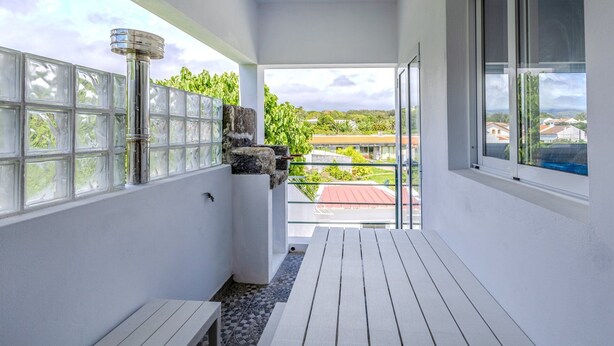 En balkon med udsigt over kvarteret, et lille bord og en potteplante.