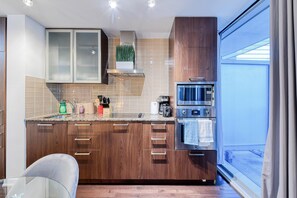 A modern kitchen with wooden cabinets, a microwave, and a coffee maker. - Aster Bay Hotel (Toronto)