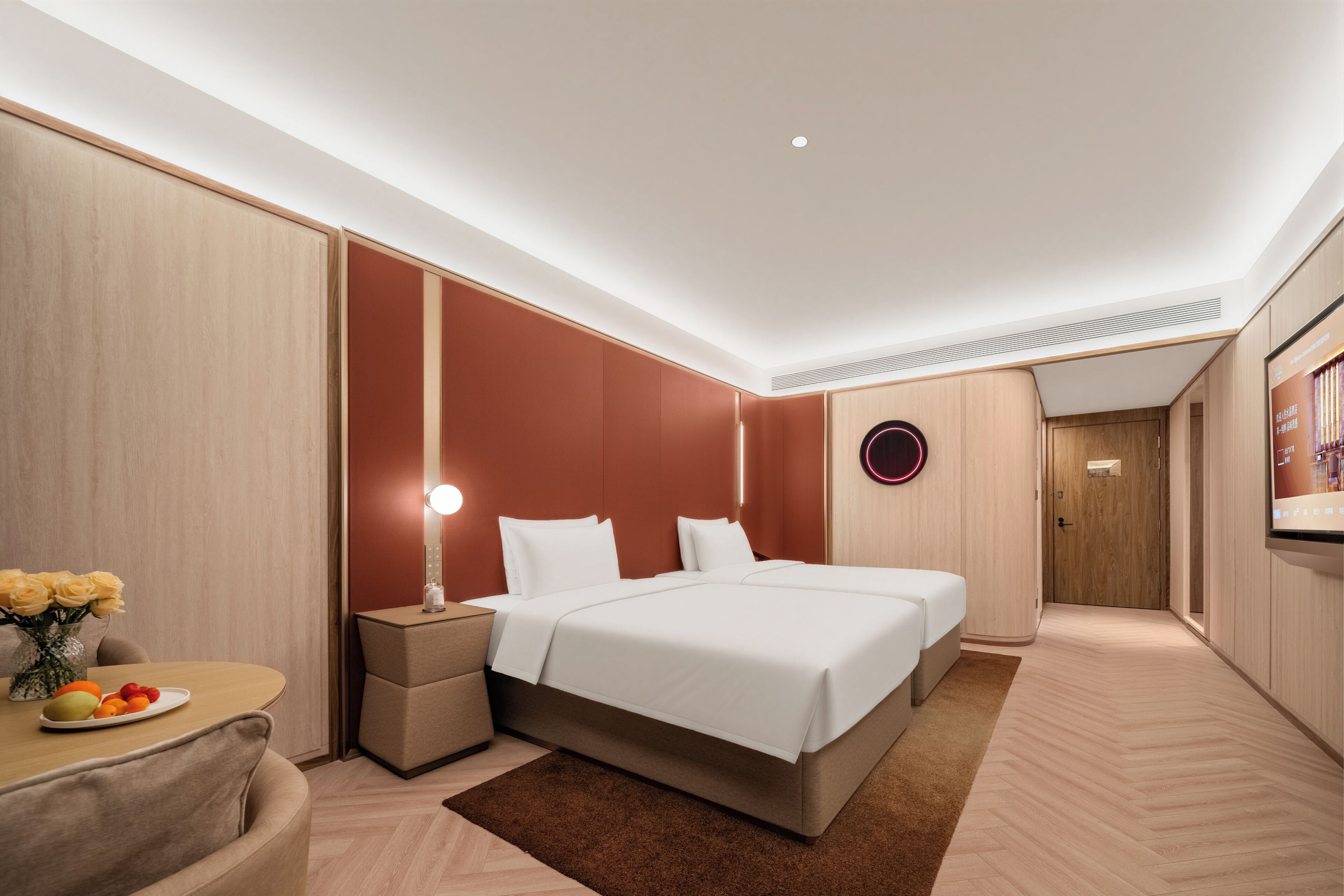 Quarto de hotel moderno com uma cama grande, mesas de cabeceira, um pequeno espaço de estar e uma televisão.