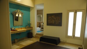 A bathroom with a mirror, sink, and a painting on the wall.