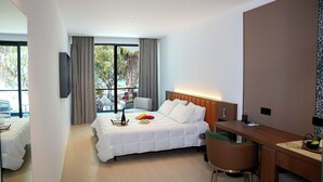 A hotel room with a bed, a desk, a chair, a TV, and a window with curtains.
