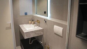 A modern bathroom with a white sink, a mirror, and a towel rack.