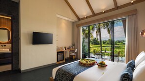 Habitación de hotel con una cama grande, televisión, escritorio y balcón con vistas al paisaje.