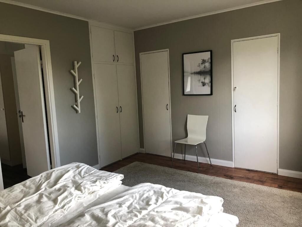 A bedroom with a bed, a chair, and a wardrobe.