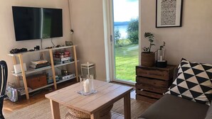 A living room with a sofa, a coffee table, a TV, a bookshelf, and a view of the outdoors.