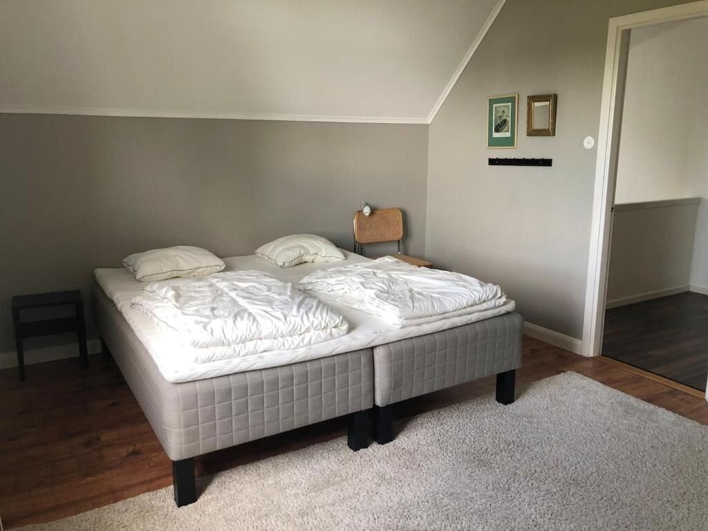 Een slaapkamer met een groot bed, een klein tafeltje en een stoel.