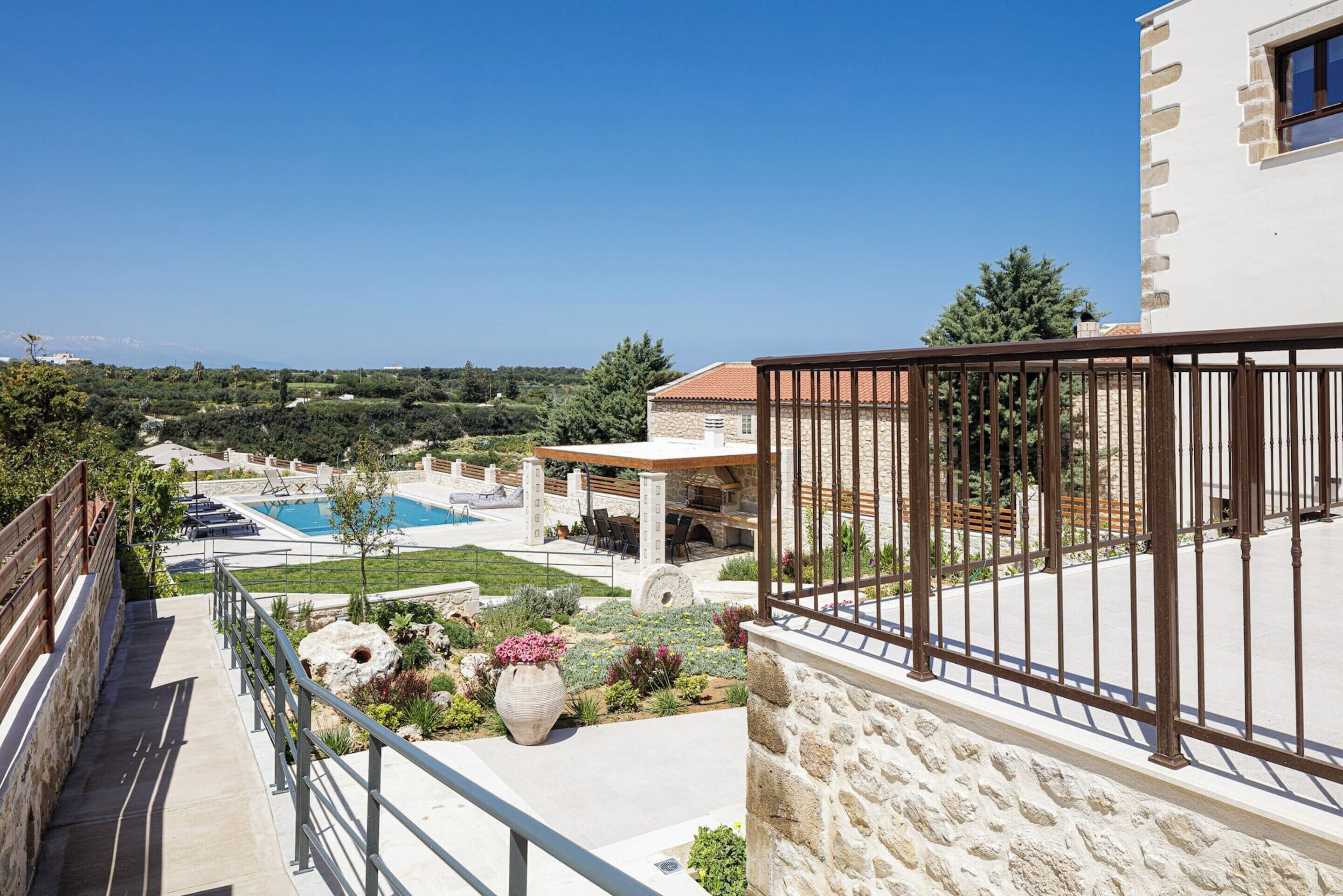 Un balcone con parete in pietra, area piscina con barbecue e vista sul paesaggio.