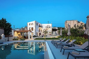 A poolside area with lounge chairs and a pool, a building with stone facade, and a clear sky. - New Luxurious Villa With Stunning Pool,views &bbq! (Rethymno)