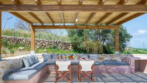 En uteplats med en träpergola, en stenmur och en sittgrupp.