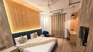 A modern hotel room with a bed, bedside table, TV, and a wooden accent wall. - Townhouse Rambagh Amritsar (Amritsar)