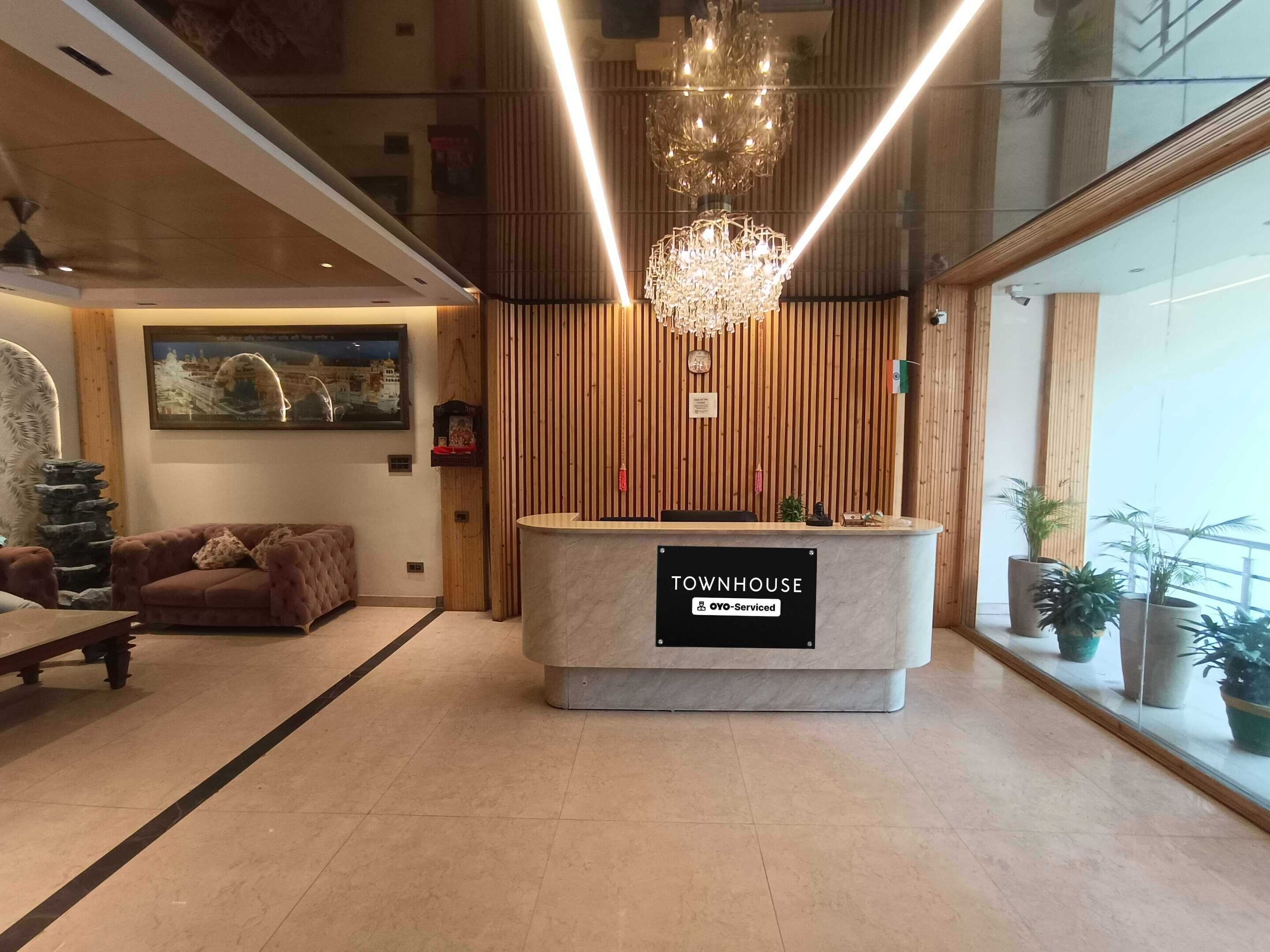 A reception desk labeled 'TOWNHOUSE' with a chandelier, wooden paneling, a sofa, and potted plants.