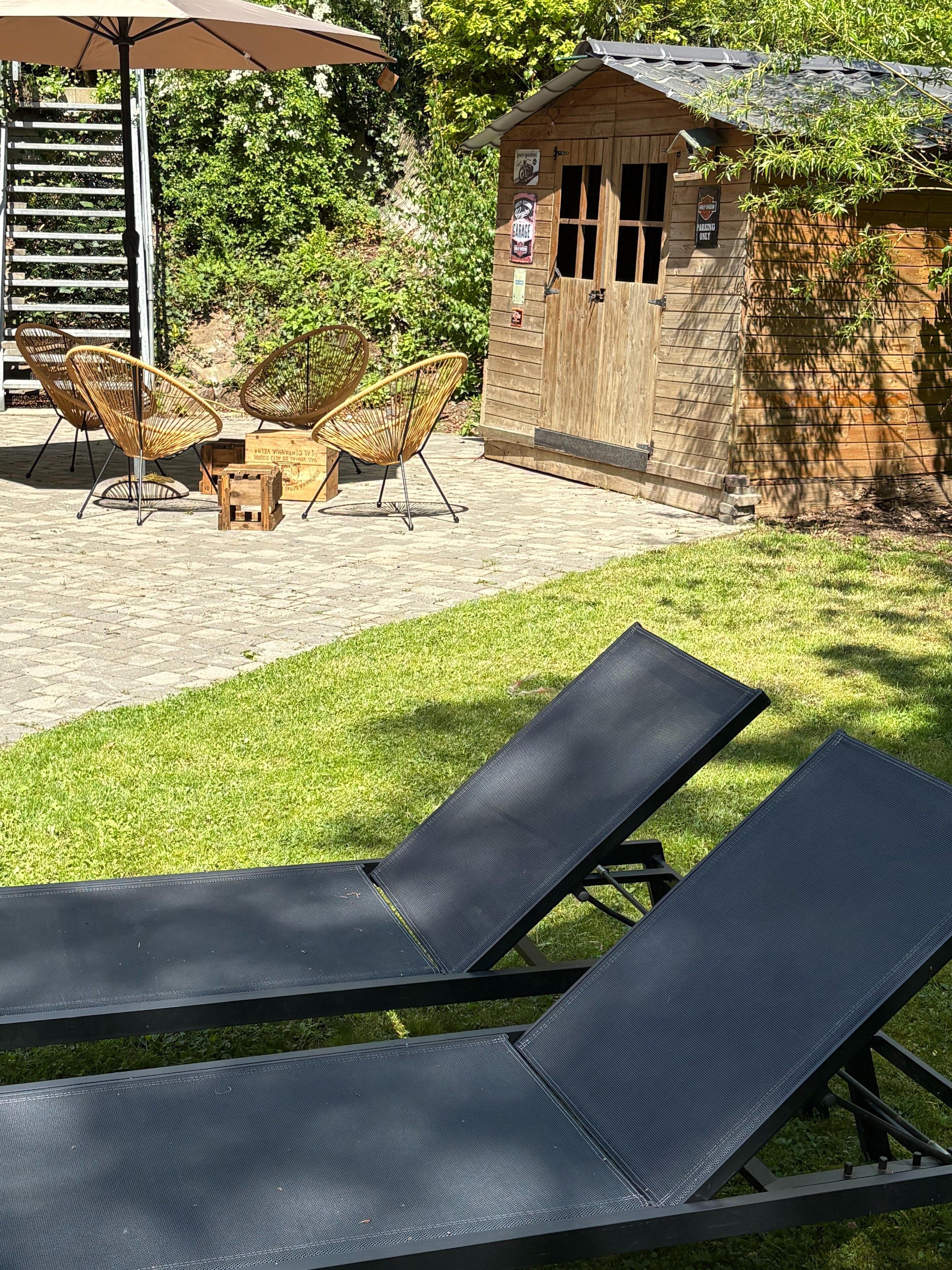 Un espace patio aménagé avec des fauteuils, une table et des chaises.