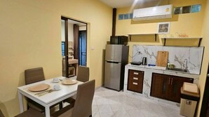 Cocina compacta con comedor, refrigerador, microondas y cubo de basura.