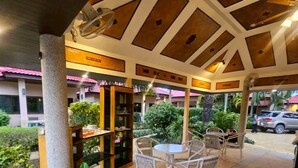 Un patio al aire libre con una zona de estar cubierta, un pequeño estante y una planta en maceta.