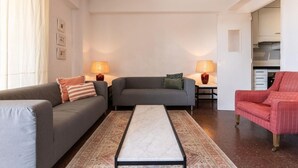 Una sala de estar con un sofá, un sillón rojo, una mesita de centro y dos lámparas.