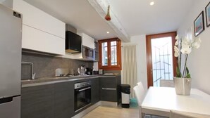 Eine moderne Küche mit integrierten Geräten, ein Essbereich mit Tisch und Stühlen sowie ein Fenster mit Blick.
