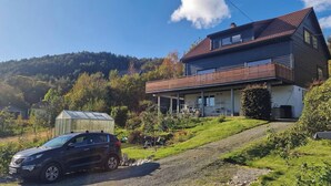 A two-story house with a sloped roof, a covered greenhouse, and a parked car on a driveway. - Charming House, 8 Beds, Possibility to Rent a Boat (Bjørnafjorden)