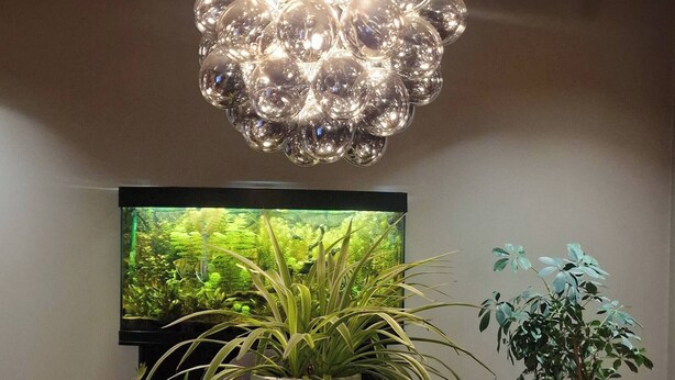 A dining area with a round table, chairs, a potted plant, a television, and a unique spherical chandelier. - Charming House, 8 Beds, Possibility to Rent a Boat (Bjørnafjorden)
