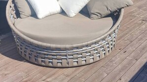 A round wicker sofa with cushions on a wooden deck, a window, and a building with horizontal siding. - Charming House, 8 Beds, Possibility to Rent a Boat (Bjørnafjorden)