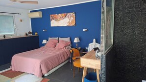 Ein Schlafzimmer mit einem Bett, einem Nachttisch, einem Stuhl, einem Schreibtisch und einem großen Spiegel.