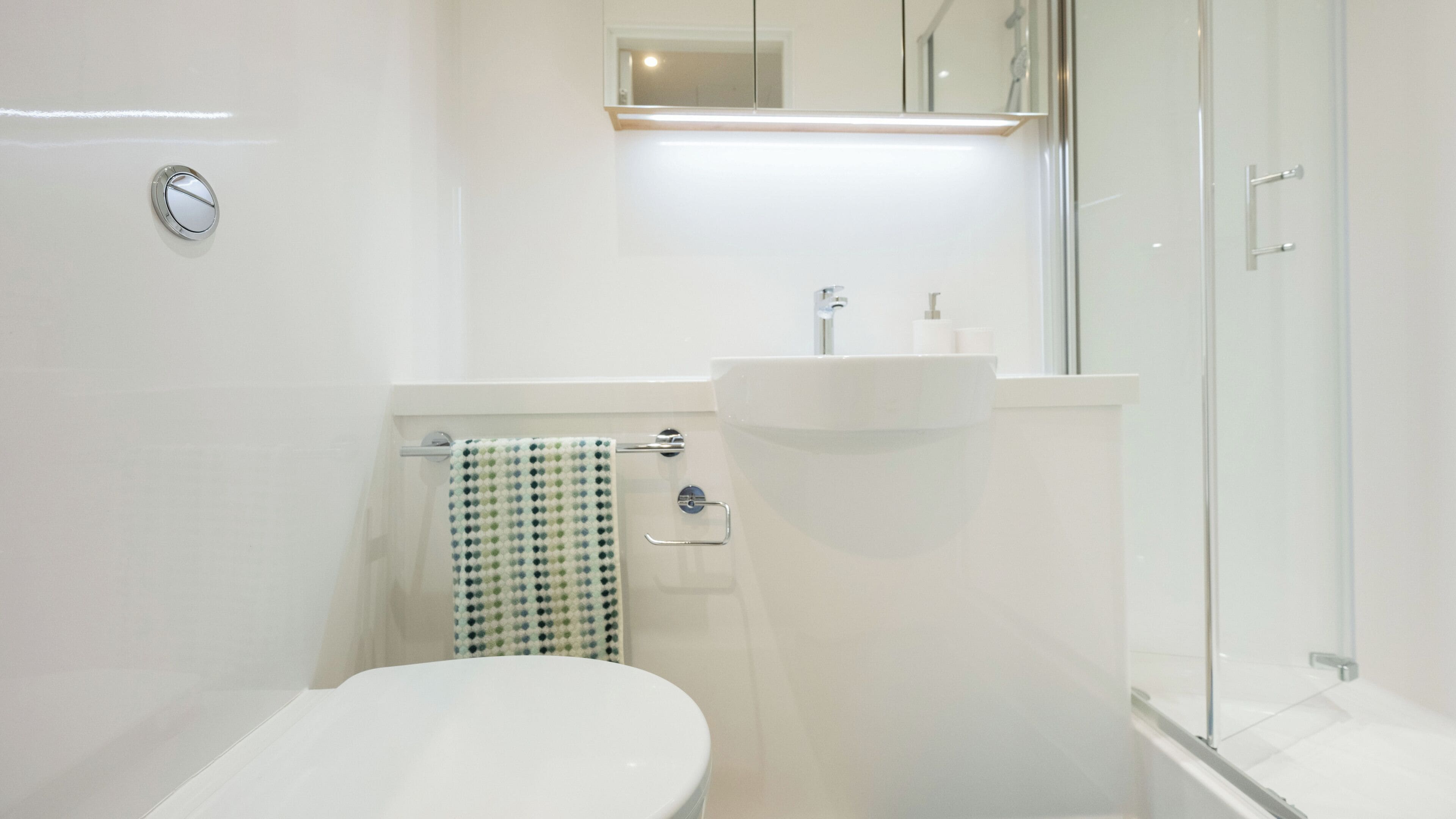 Un baño moderno con inodoro, lavabo y cabina de ducha de vidrio.