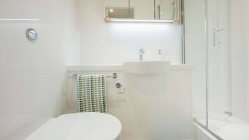 Un baño moderno con inodoro, lavabo y cabina de ducha de vidrio.