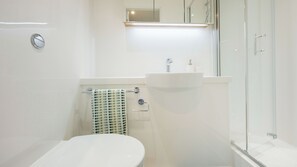 A modern bathroom with a toilet, sink, and glass shower enclosure.