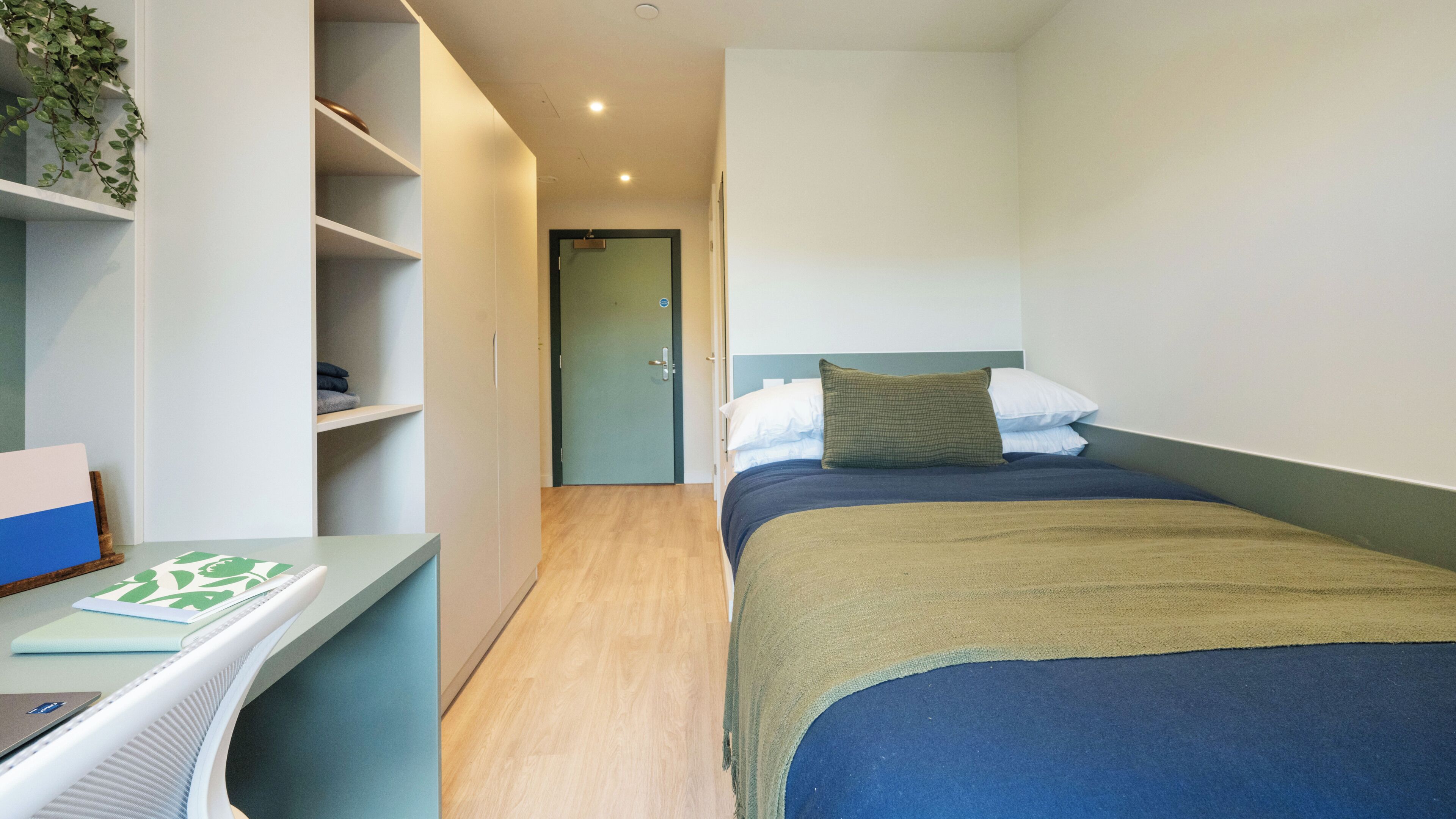 Een slaapkamer met een bed, een bureau en een deur naar een andere kamer.
