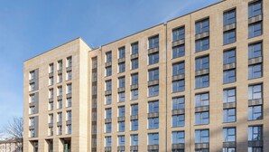 Un edificio de varios pisos con fachada uniforme, numerosas ventanas y techo plano.