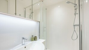 A modern bathroom with a glass shower enclosure, a white sink, and a mirror. - For Students Only - City Wharf in Glasgow (Glasgow)