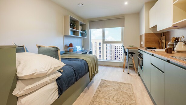 A modern bedroom with a bed, bedside table, and a view of a cityscape through a large window. - For Students Only - City Wharf in Glasgow (Glasgow)