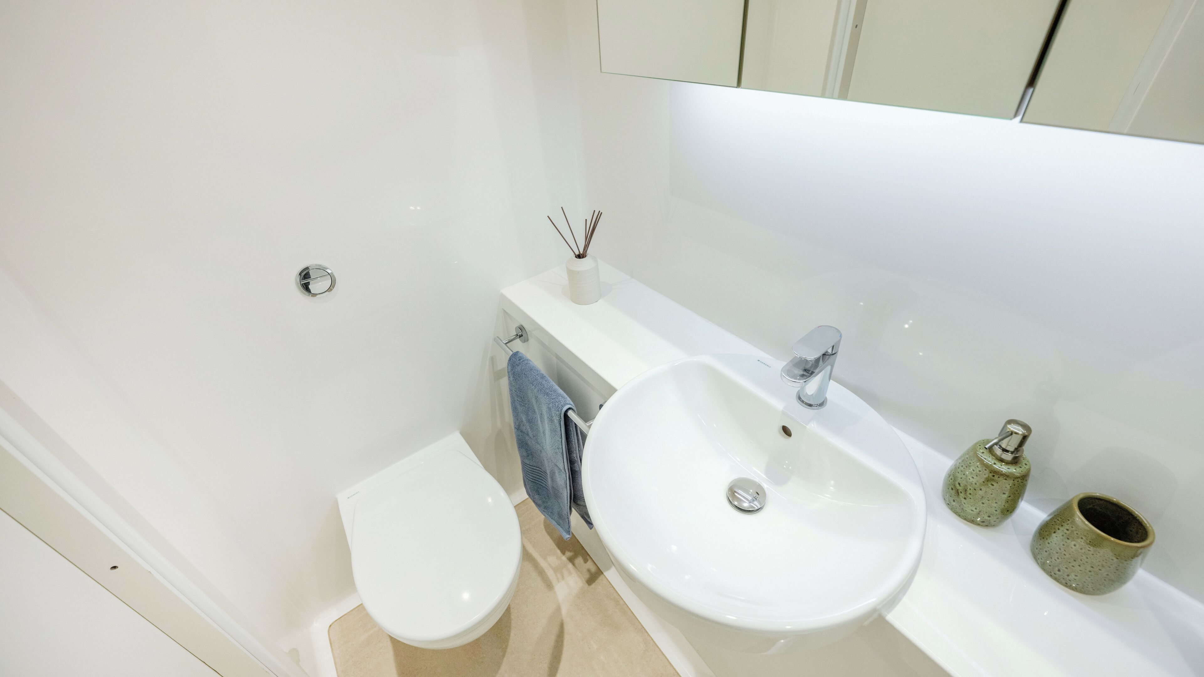 A bathroom with a toilet, sink, and mirror.