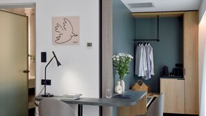 Une cuisine moderne avec des meubles en bois, un porte-vêtements suspendu et une machine à café.