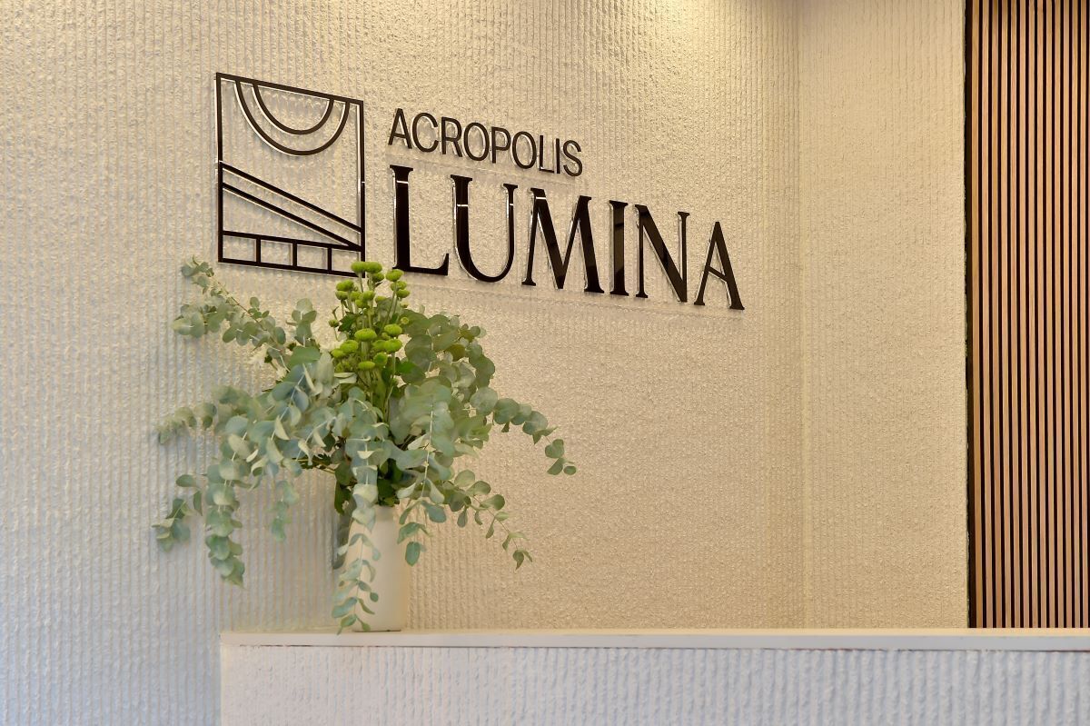 Una pared con el texto 'ACROPOLIS LUMINA' y una planta en maceta.