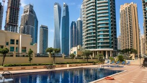 Una piscina con sillones de descanso y una mesa, rodeada de edificios altos.