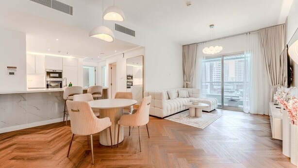 Una sala de estar moderna con un sofá, una mesa de comedor con sillas y una zona de cocina.