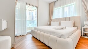 Un dormitorio moderno con una cama grande, una mesita de noche y un ventanal con cortinas.