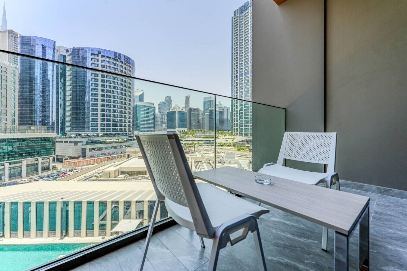Un balcone con tavolo e sedie, vista sulla città e piscina.