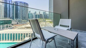 A balcony with a table and chairs, a city view, and a pool. - HAVN - Studio in Peninsula 2, Business Bay (Dubai)