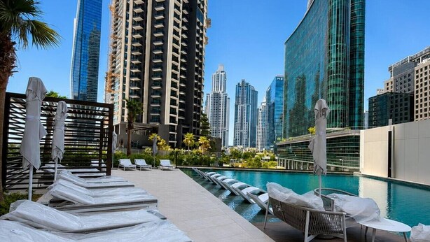 A rooftop pool with lounge chairs and umbrellas, surrounded by high-rise buildings. - HAVN - Studio in Peninsula 2, Business Bay (Dubai)