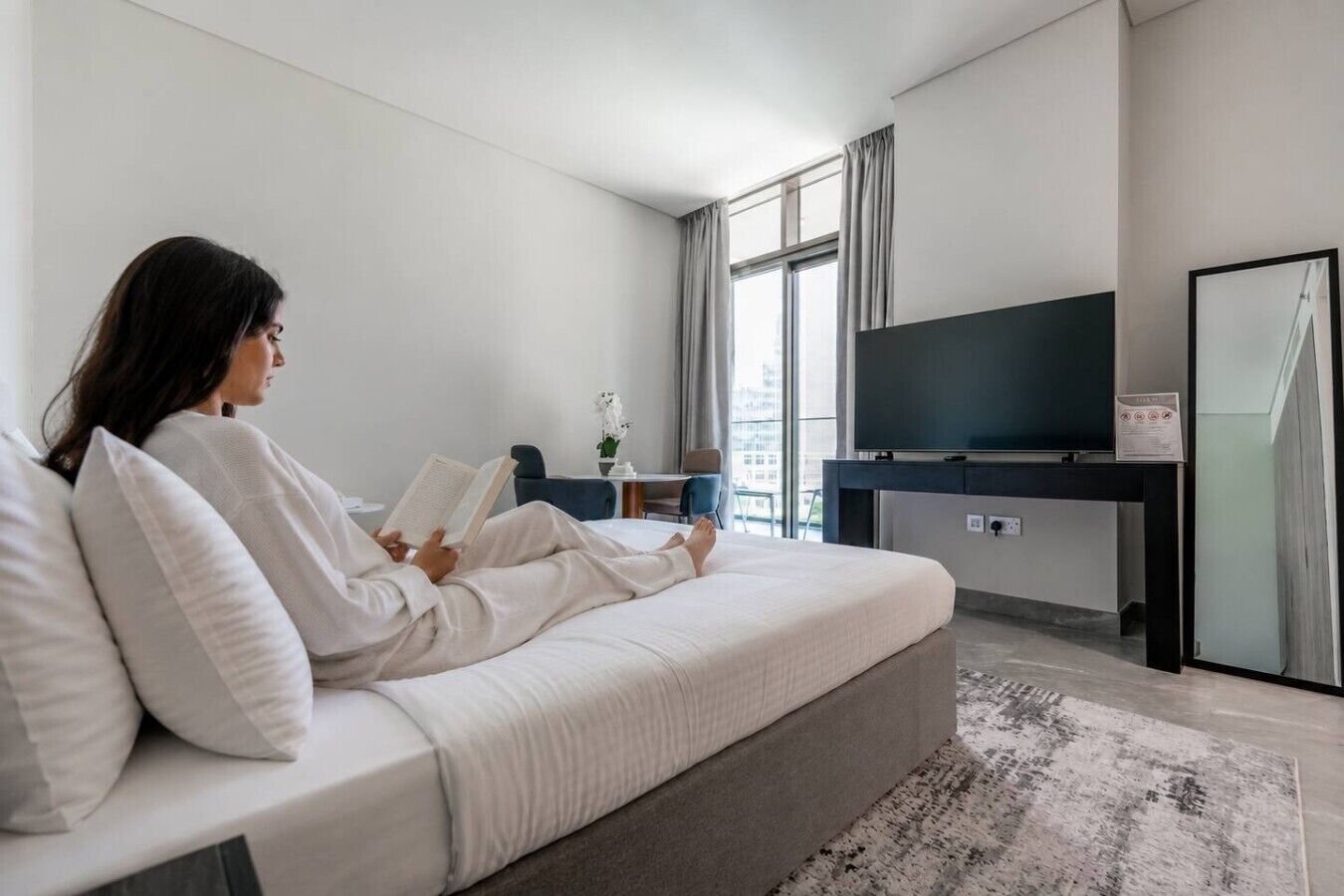A modern living room with a sofa, a flat-screen TV, and a large window.