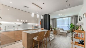 Une cuisine moderne dotée d’un îlot central, de tabourets de bar et de luminaires suspendus.