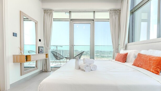 Una camera d'albergo moderna con un letto grande, un balcone vista e un'ampia finestra.